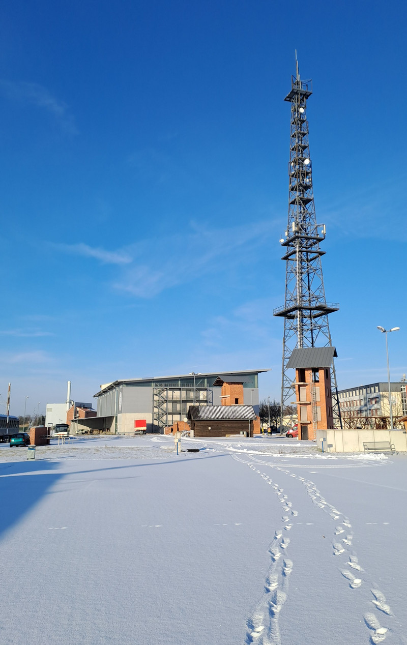 Außengelände mit Funkmast und großer Halle mit Schnee bedeckt.