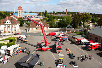 In dieser Luftaufnahme wird ein großer Platz mit verschiedenen Hilfsfahrzeugen der Personenrettung und Feuerwehren gezeigt. Im Hintergrund ist Quedlinburg mit mehreren Gebäuden. 