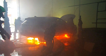 Flammen sind unter einem E-Auto zu sehen bei einem Brandversuch