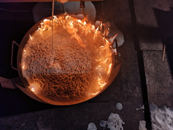 Brandwanne von oben. Eine brennende Flüssigkeit wird von Löschschaum bedeckt.