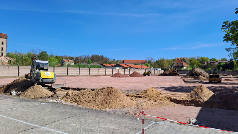 der neue Sportplatz wird hergerichtet. Dazu transportieren Baumaschinen wie Bagger Erde.