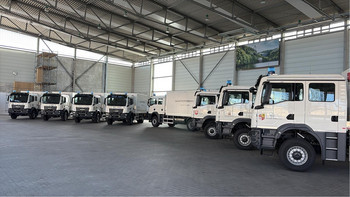 8 weiße LKW, die Gerätewagen Betreuung, stehen in der Übungshalle des IBK