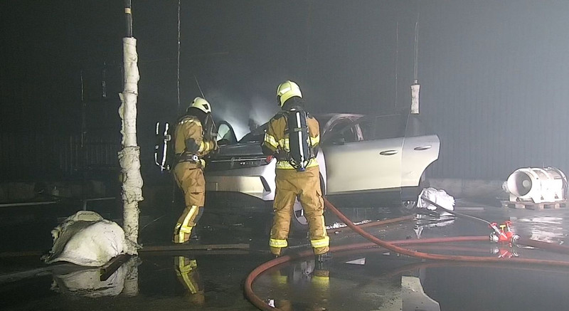 2 Feuerwehrmänner öffnen eine Motorhaube eines Fahrzeugs bei einem Brandversuch