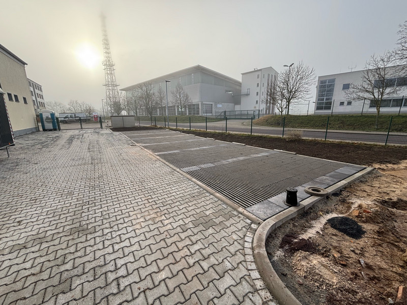 neu gepflasterte Fläche, die Umzäunt ist. Im Hintergrund ist ein Telefonmast zu sehen.