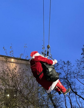 ein Mann als Weihnachtsmann verkleidet hängt an Seilen zum Abseilen