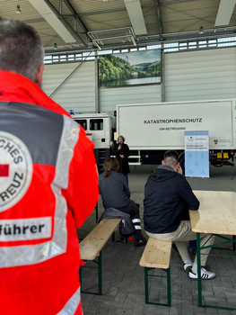 Ministerin hält Rede vor LKW. Davor sitzen und stehen Zuhörer.