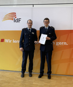 Urkunde und Schuterstücken werden an neuen Brandrat überreicht