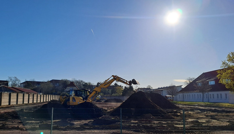 Sportplatz auf dem große Erdhaufen liegen und auf dem Bagger arbeiten