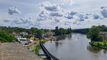 Blick von einer Erhöhung auf die Saale und das Festegelände mit vielen Fahrgeschäften und besuchern 
