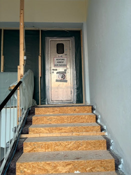 mit Holz abgedeckte Treppe und mit Bautür abgetrennter Bereich