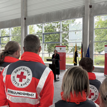 Personal von Rettungsdienstorganisatoren hört der sachsen-anhaltinischen Innenministerin bei einer Reder zur Übergabe von Einsatzleitwagen zu.