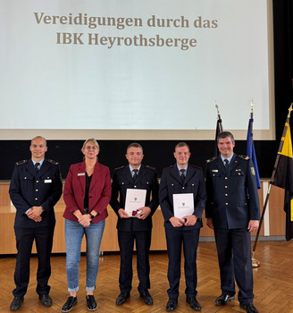 5 Personen (4 Männer, 1 Frau) vor einer Präsentation mit der Aufschrift "Vereidigungen durch das IBK Heyrothsberge